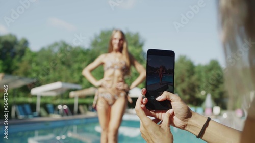 Girl with inflated press in bikini posing for photos on a mobile phone