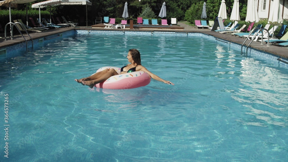 Woman is floating with an inflatable donut circle in the swomming pool