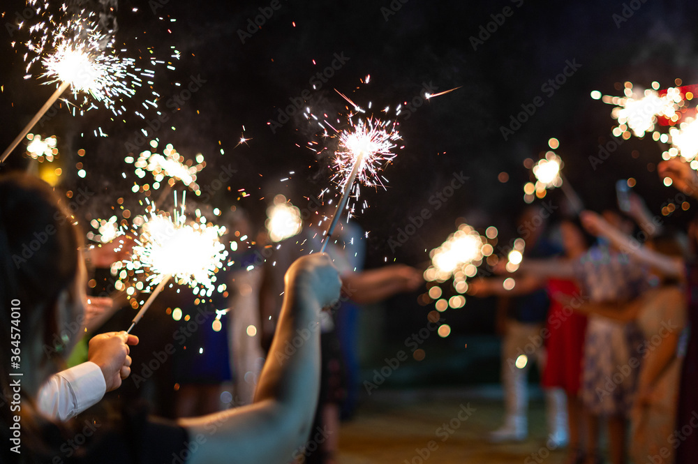 festive burning bright sparklers in the hands of guests at a party. New Year or wedding celebration. fun