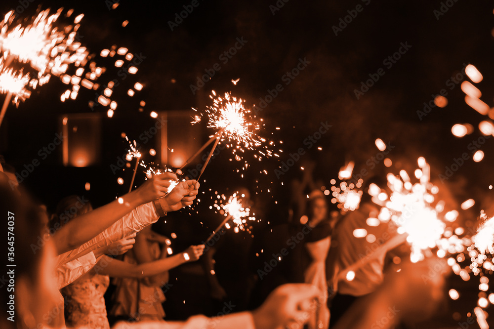 festive burning bright sparklers in the hands of guests at a party. New Year or wedding celebration. holiday parties