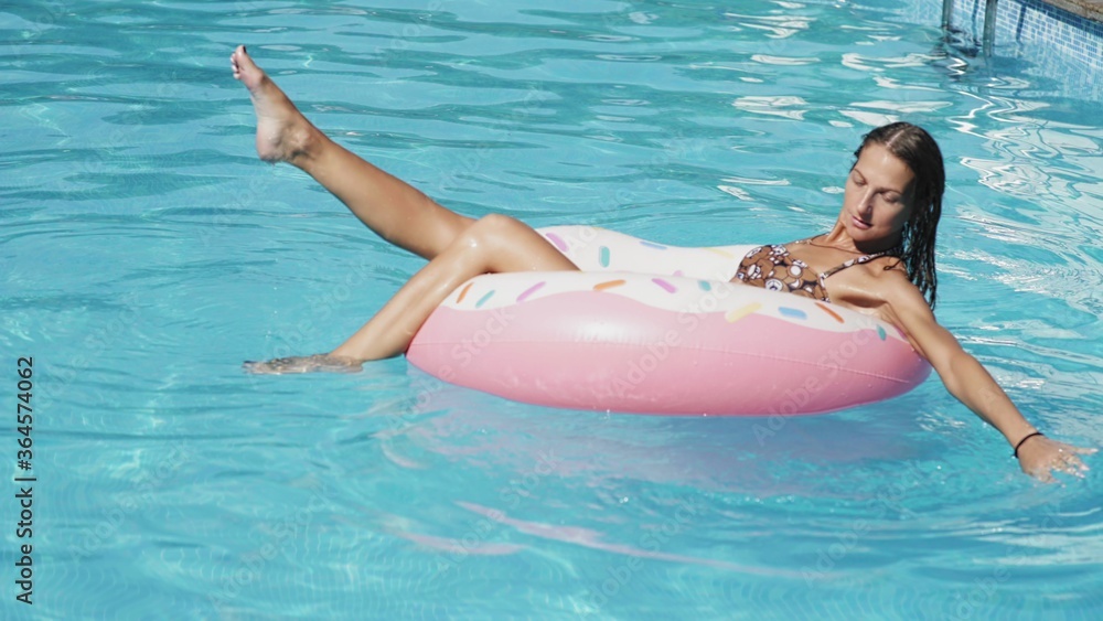 Sexy attractive woman is swimming on the inflatable rubber ring in the pool
