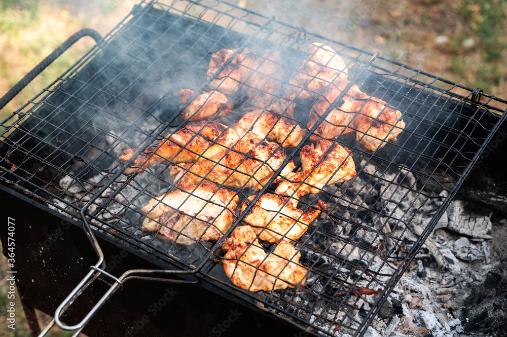 pickled chicken fried on a black dirty grill on a picnic. harmful fatty foods. backyard barbecue party