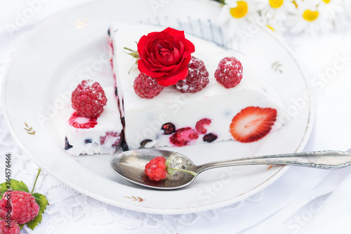 Dessert of yogurt , berries and gelatin, decorated with raw raspberries and natural red rose in white background, fresh, healthy food 