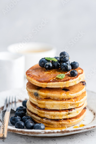 Blueberry pancakes with honey on plate. Stack of fluffy pancakes. Tasty sweet breakfast food