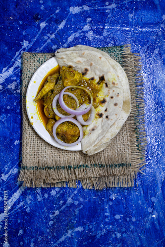 Mangsho Kosha or Chicken Curry with Roti in a Plate Isolated Bluish Background in Vertical Orientation photo