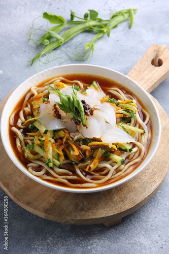 Eastern oriental cuisine, Asian cuisine. Cold soup ashlam fu. Soup with noodles, starch and vegetables. Spicy soup on a light grey background and in a white plate. Background image, copy space