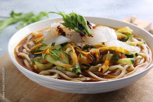 Eastern oriental cuisine, Asian cuisine. Cold soup ashlam fu. Soup with noodles, starch and vegetables. Spicy soup on a light grey background and in a white plate. Background image, copy space photo