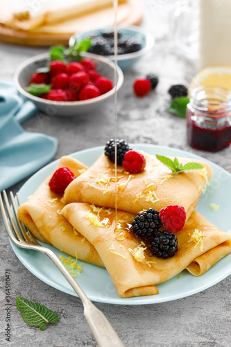 Thin crepes with fresh berries and lemon zest. Pancakes with raspberry and blackberry. photo