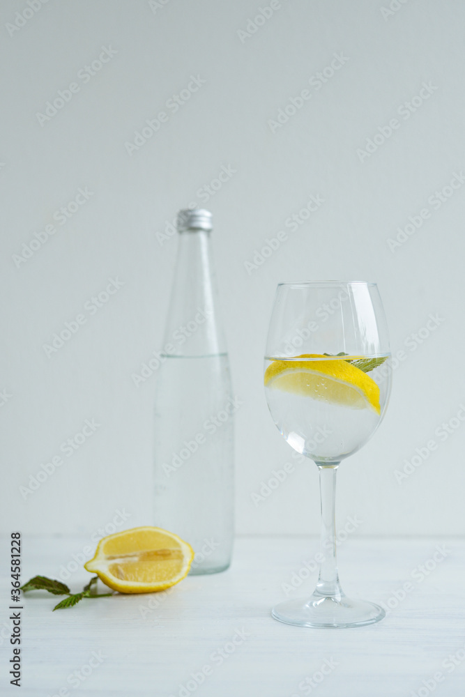 Glass of cold water with lemon and mint standing on the white background