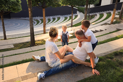 Family summer leisure in the park. mom dad and two sons have fun and play.