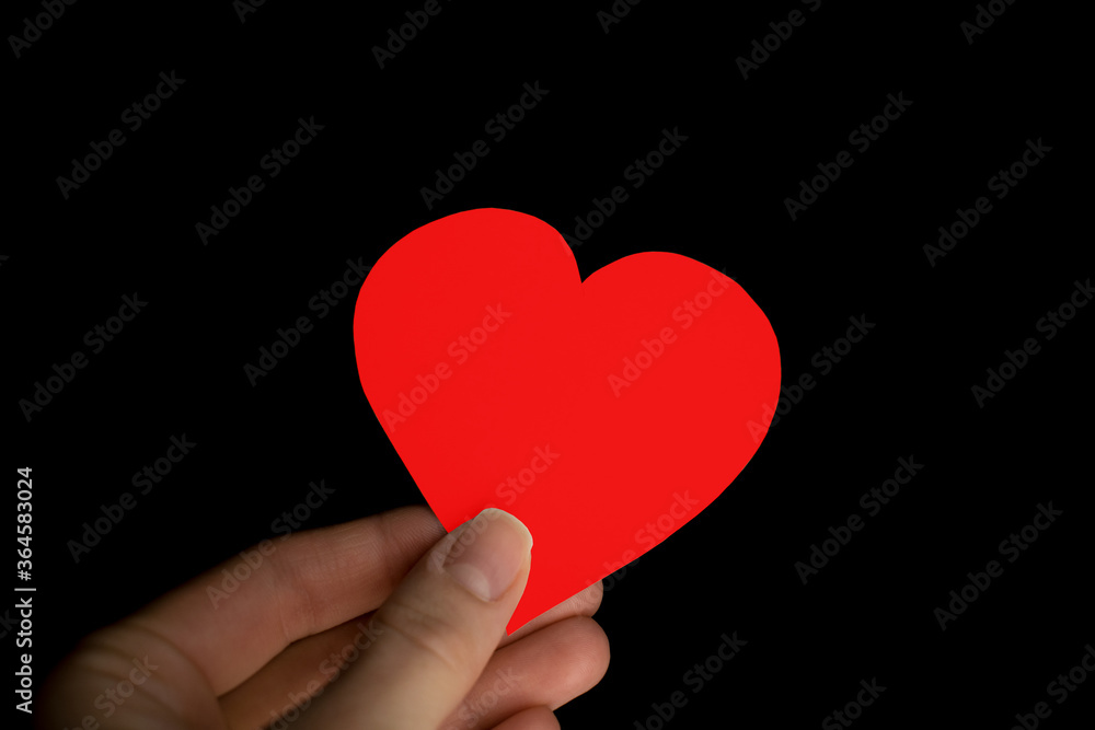 Red heart in hand on black background. Valentine concept close-up Red heart in hand on black background. Valentine concept close-up