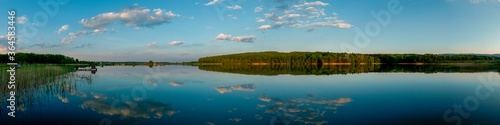 Panoramic landscape from the lake with colorful clouds in the summer sun.