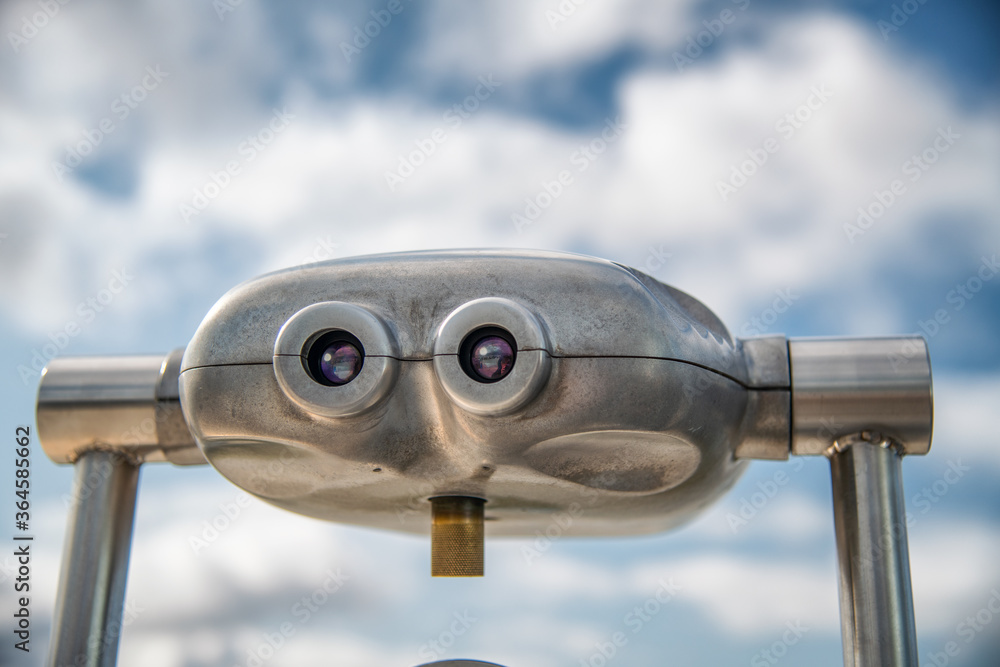 Metal binoculars with blue sky in background. Tourism concept