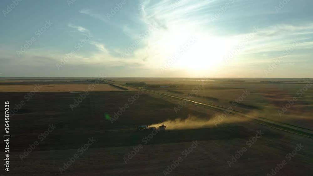 Dust From A Working Seeder Tractor In Saskatchewan, Canada On A Sunset - aerial drone Dust From A Working Seeder Tractor In Saskatchewan, Canada On A Sunset - aerial drone