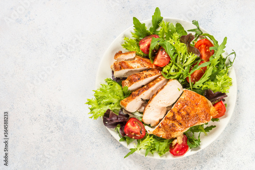 Grilled chicken with fresh salad at table.