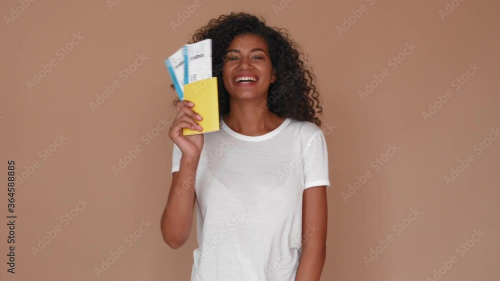 smiling black woman with plane tickets and passport isolated over brown smiling black woman with plane tickets and passport isolated over brown