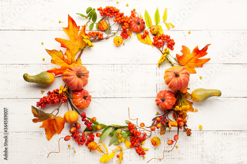 Autumn concept with pumpkins  flowers  autumn leaves and  rowan berries on a white rustic background. Festive autumn decor  flat lay with copy space.