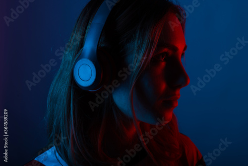 Photo of young woman listening music at headphones with neon lights