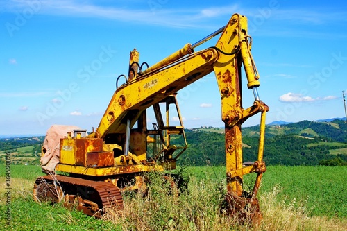 Old abandoned yellow excavator on the field.