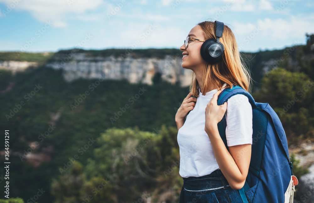© A_B_C - positive young traveler girl with headphones and backpack stands on top of mountain, active tourist woman hiking enjoys beautiful landscape and . fresh air high in mount, empty space for text © A_B_C - positive young traveler girl with headphones and backpack stands on top of mountain, active tourist woman hiking enjoys beautiful landscape and . fresh air high in mount, empty space for text
