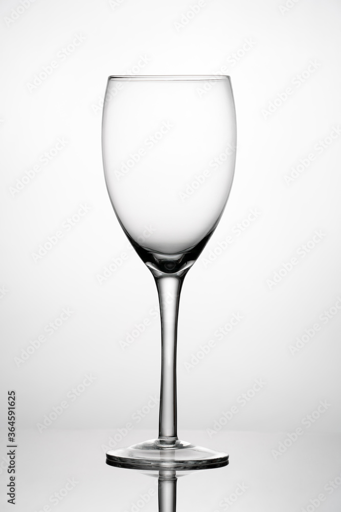 Empty wine glass on reflective surface. White background with gray vignette Empty wine glass on reflective surface. White background with gray vignette