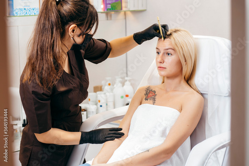 Beautician female carries out the correction of eyebrows on beautiful models in cosmetic cabinete