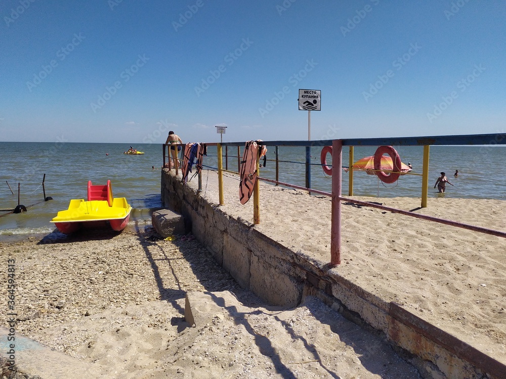 Obraz premium Yellow red catamaran near the pier on the beach