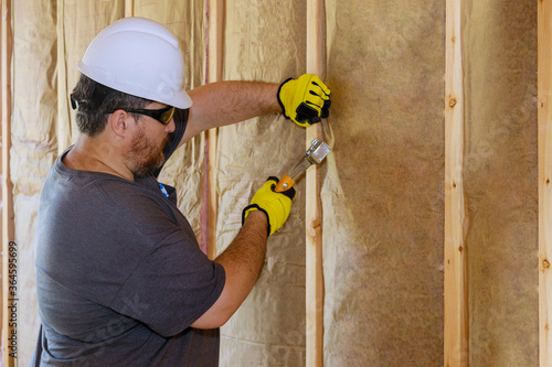 Man installing thermal insulation layer under the wall using mineral wool