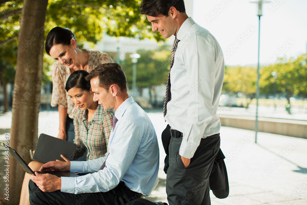 Business people using laptop in urban park Business people using laptop in urban park