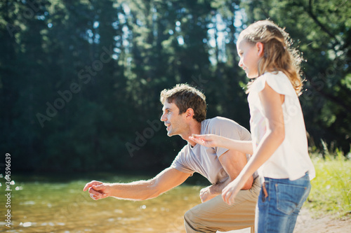 Canvas-taulu Father and daughter skipping stones at lakeside