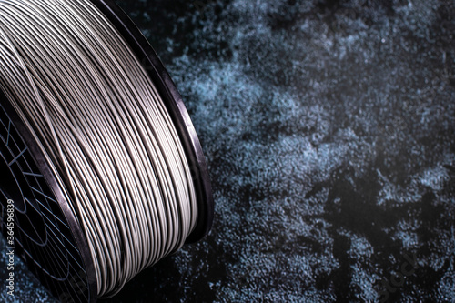 A coil of filament for 3d printing. Bright thermoplastic of grey color. Reel vertical view. photo