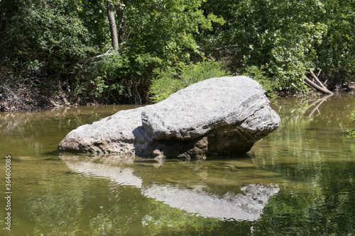 a large rock reflecting in the middle of a stream