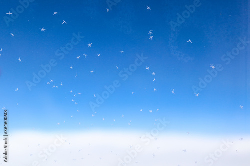 snowflakes on the airplane window glass, with beautiful blue sky in the background