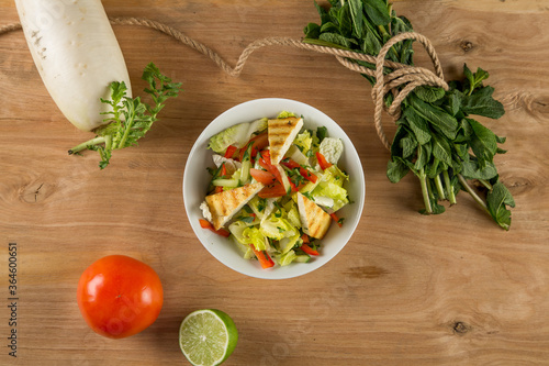 Fresh vegetable salad seasoned with oil on a wooden background
