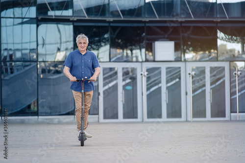 Senior man riding electric scooter in a cityscape 