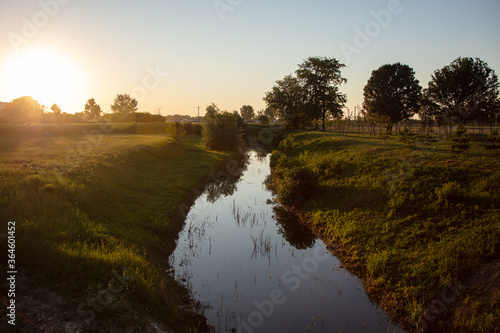 Fototapeta Naklejka Na Ścianę i Meble -  landscape, a small river at dusk with the golden colors from the sun