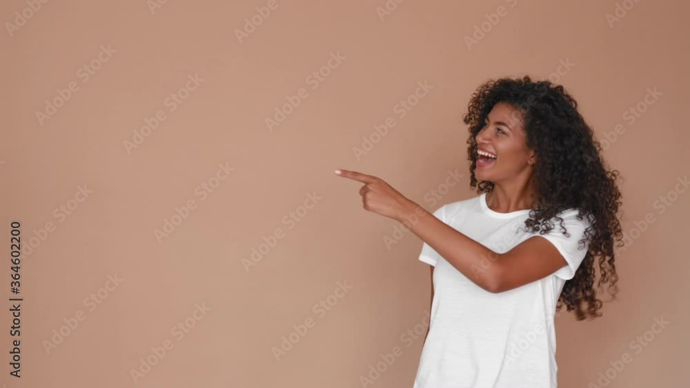 excited black woman pointing finger at copyspace and showing thumbs up and smiling on brown background excited black woman pointing finger at copyspace and showing thumbs up and smiling on brown background
