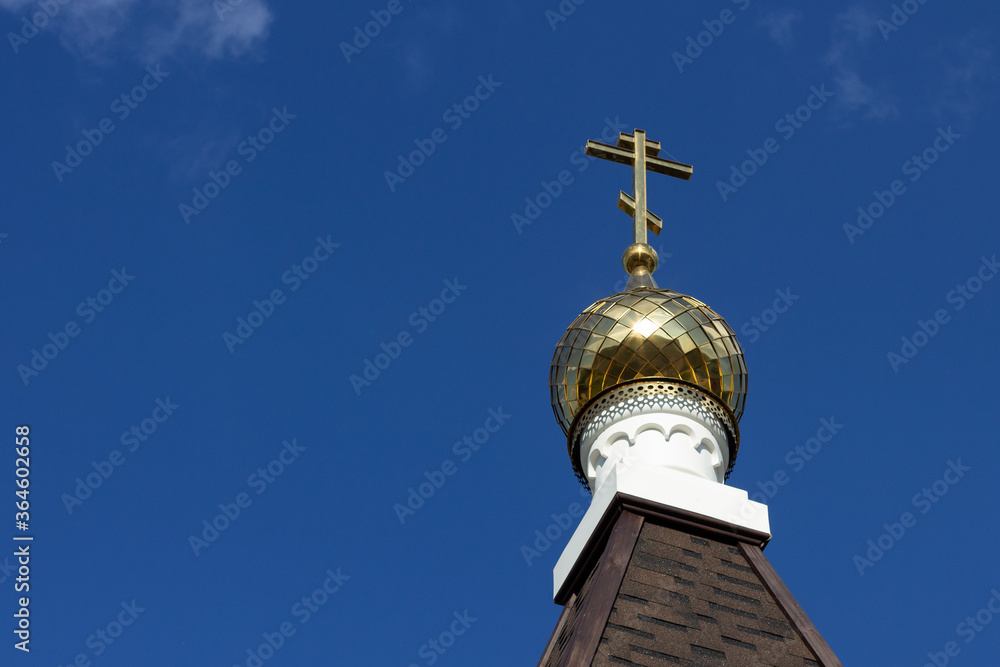 
Golden dome with a cross on the roof of the church against the blue sky