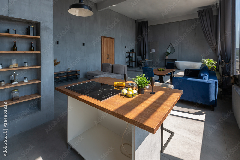 Modern minimalistic dark gray loft style studio apartment interior design. kitchen, sitting area, workplace, shower and bath. bright sun rays inside. Modern minimalistic dark gray loft style studio apartment interior design. kitchen, sitting area, workplace, shower and bath. bright sun rays inside.