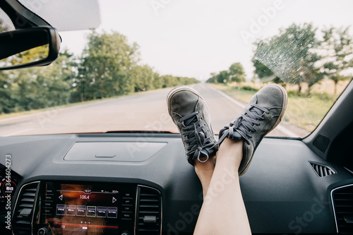 Female feet on a car dashboard by the windshield. Road trip concept. photo