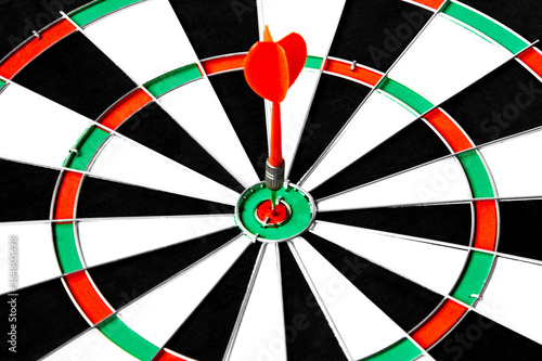 Close up shot red dart arrow on center of dartboard, metaphor to target success, winner concept, Isolated on white background with clipping path