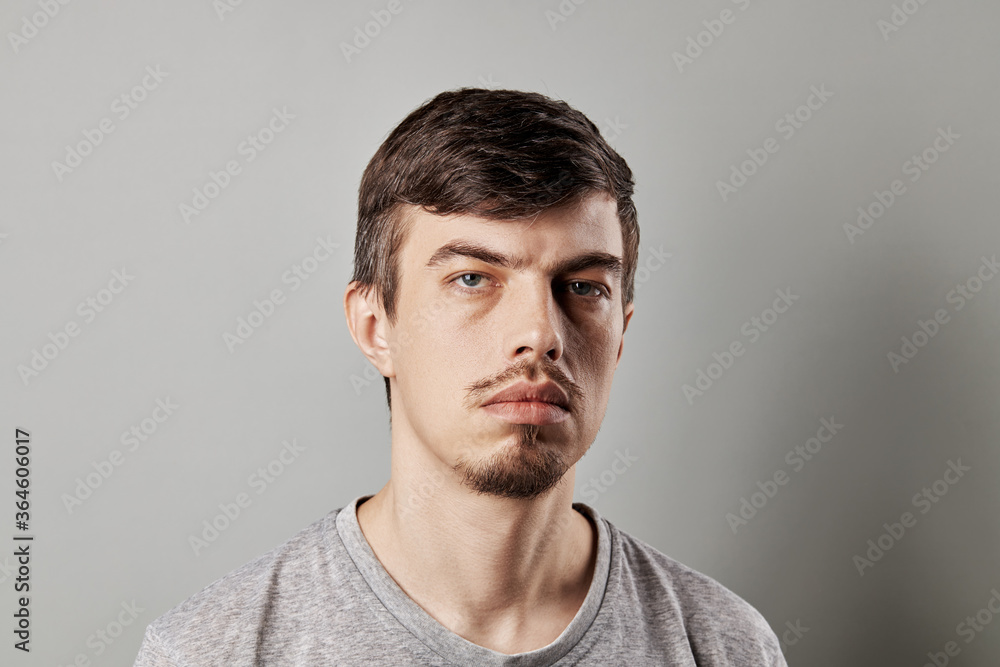 Fototapeta premium Portrait of a middle-aged European guy with a serious facial expression. studio shot isolated over grey background. copy space. sad blue eyes, tiny bread. natural people.