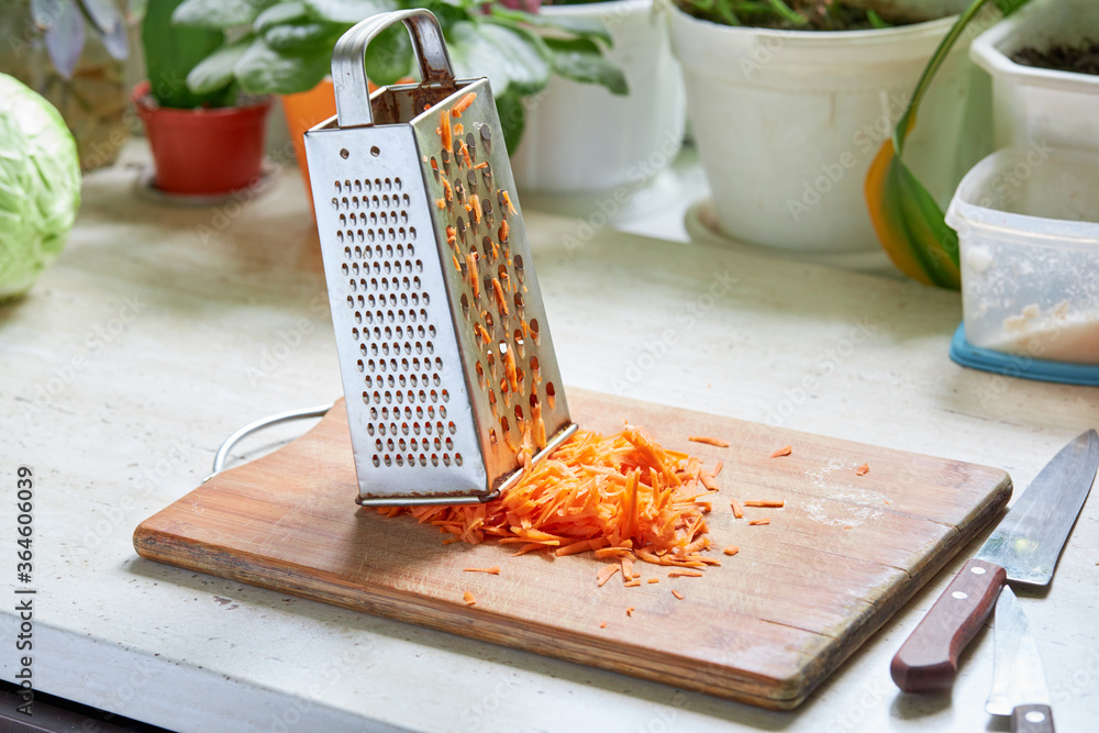Φωτογραφία rubbed carrot on a cooking board at kitchen table