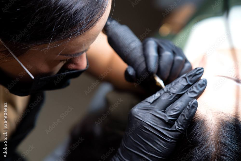 The girl artist paints an eyebrow tattoo. The process of tattooing. Permanent makeup The girl artist paints an eyebrow tattoo. The process of tattooing. Permanent makeup