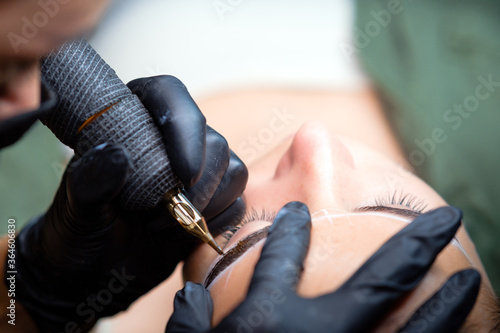 The girl artist paints an eyebrow tattoo. The process of tattooing. Permanent makeup	