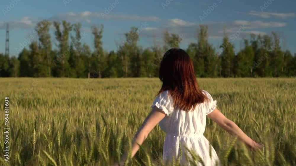A young woman runs across the field in a white dress. Happy girl in a green wheat field. Slow motion. A young woman runs across the field in a white dress. Happy girl in a green wheat field. Slow motion.