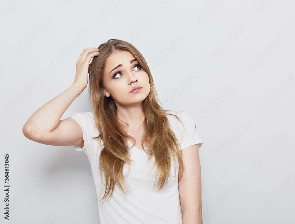 Thinking blond doubt young woman looking up and thinking on light blue background. Closeup portrait Thinking blond doubt young woman looking up and thinking on light blue background. Closeup portrait