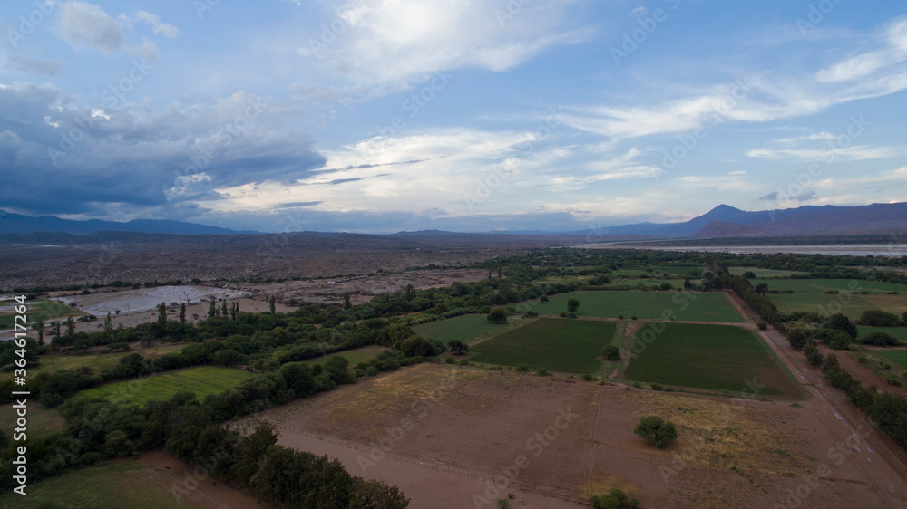 Rural landscape. Aerial view of the alfalfa and crop plantation fields and farmland in the mountains, under a dramatic sky with beautiful clouds at sunrise. 