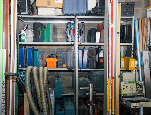 Rack in a carpentry workshop on which there are many different suitcases and boxes with tools, side view close-up.