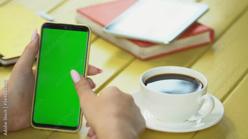 business woman using smartphone viewing green screen on mobile phone browsing chroma key online watching enjoying drinking coffee reading social media close up hands business woman using smartphone viewing green screen on mobile phone browsing chroma key online watching enjoying drinking coffee reading social media close up hands